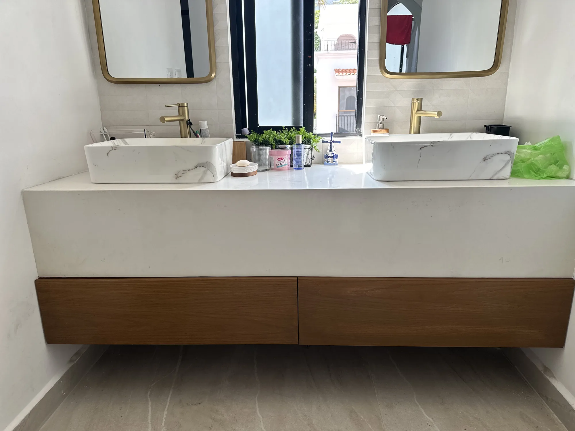 Baño off white con doble lavabo de porcelana veteada, grifería y espejos de latón y cajones de madera a la medida
