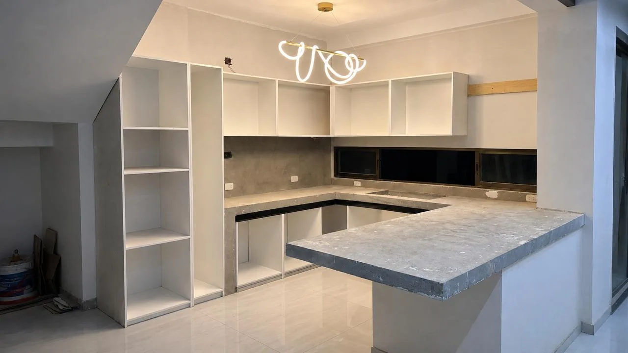 Cocina off white durante la obra, con cajas de mobiliario sin frentes y cubiertas de concreto