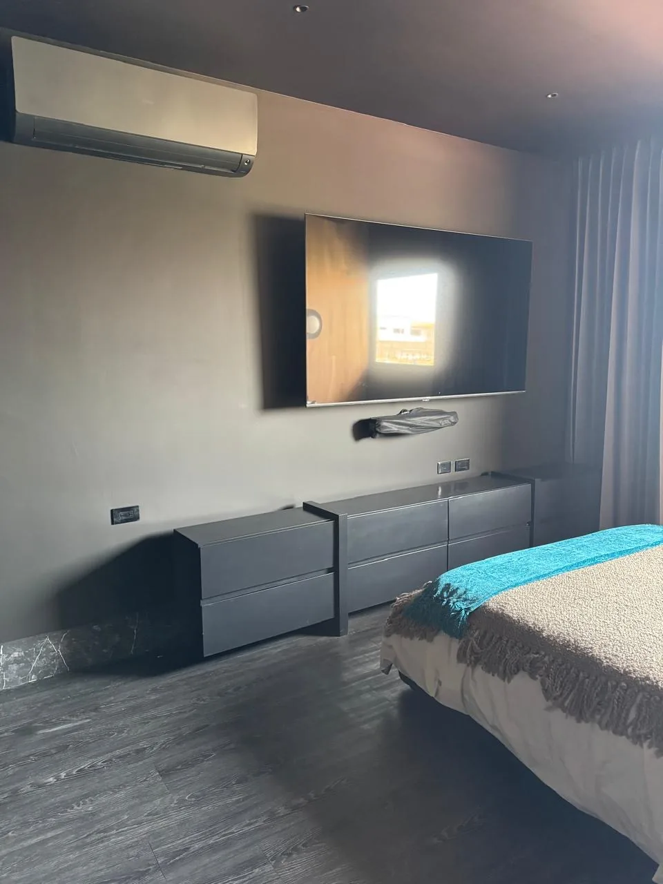 Recámara con mueble de piso en gris grafito para televisión, fabricado a la medida sobre zoclo de mármol